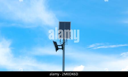 Small solar panel with digital LED lights on blue sky with sun. Solar energy from the sun. Stock Photo