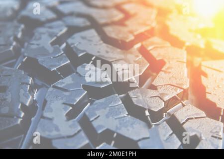 Close-up of black off-road tire tread pattern background, sun glare corner Stock Photo