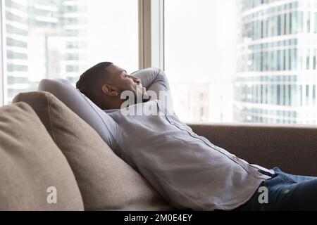 Happy young African man resting on sofa in home apartment Stock Photo