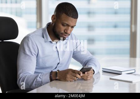 Serious young African business man reading, typing text message Stock Photo