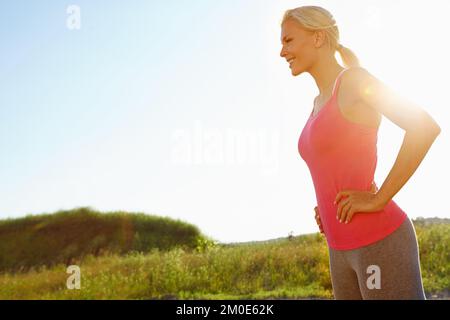 Relaxing in the beautiful countryside. A young woman in sporswear relaxing after a jog. Stock Photo
