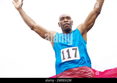 Victorious finish. Low angle view of a successful runner reaching the ribbon. Stock Photo