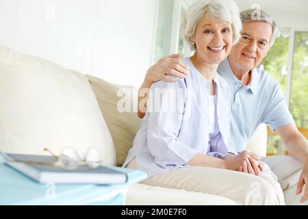 Relaxing in their living room. A loving senior couple enjoying one anothers company in their living room. Stock Photo