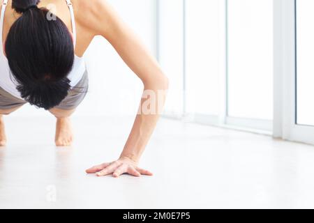 Building her upper body strength. Young woman doing push-ups indoors - copyspace. Stock Photo