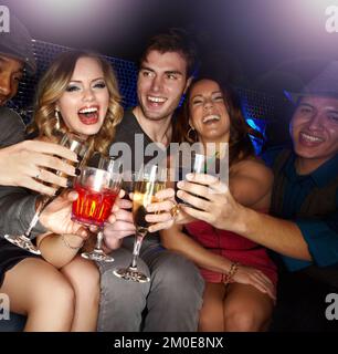The nights in full swing. An excited group of friends celebrating and drinking champagne together. Stock Photo