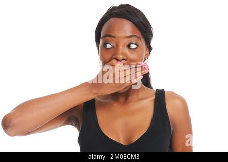 Keeping a secret isnt always easy. Young woman covering her mouth and looking shocked while isolated on white. Stock Photo