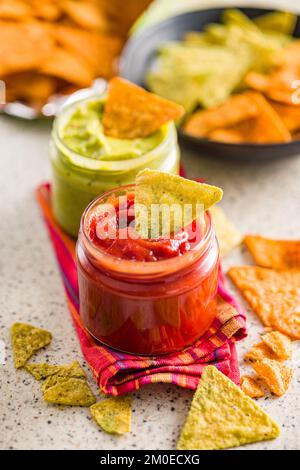 Red and green salsa with tortilla chips on the kitchen table. Stock Photo