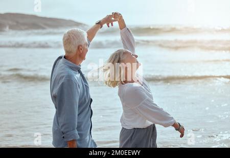 A happy mature caucasian couple enjoying fresh air on vacation at the beach. Smiling retired couple dancing outside Stock Photo
