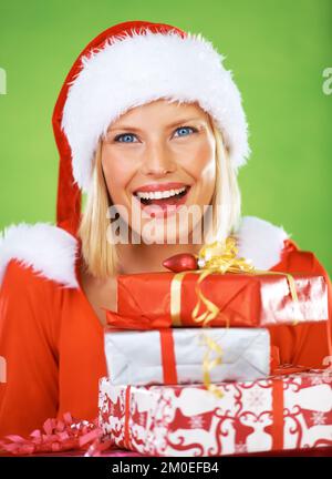 Going that extra mile, with a smile. Close-up of a beautiful young woman holding a pile of wrapped Christmas presents. Stock Photo