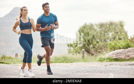 Fit young man and woman running together outdoors. Interracial couple and motivated athletes doing cardio workout while exercising for better health Stock Photo