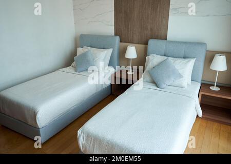 Apartment interior hotel with two single beds and bedside lamps. Stock Photo