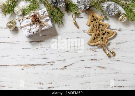 Christmas gold decor, fir tree twigs and gift box on a white wood background. View from above. Stock Photo