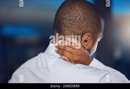 Above rearview young african man holding his neck in pain. African american business man suffering from the stress and pressure of deadlines which is Stock Photo