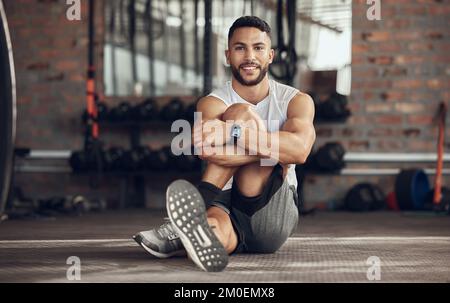 Portrait of fit man stretching before exercise. Young athlete stretching his leg before a workout. Handsome man doing a warmup in the gym. Muscular Stock Photo