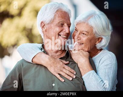 Love, romance and dating with a senior couple hugging outdoor in nature together during retirement. Relax, park and countryside with a mature man and Stock Photo