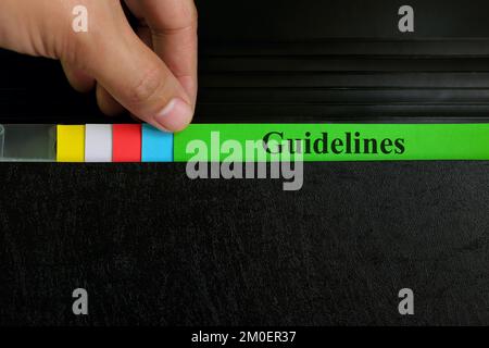 Hand picking guidelines file record in black binder folder. Work guideline concept. Stock Photo