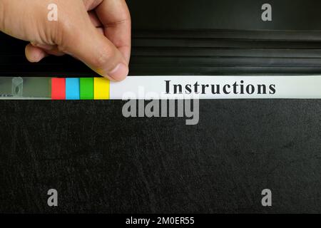 Hand picking instructions file record in black binder folder. Work instruction concept. Stock Photo