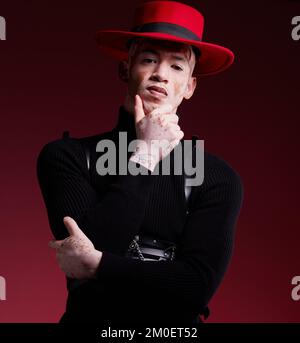 Man, fashion style or vitiligo skin on red background studio in empowerment, self love or attitude. Portrait, aesthetic or model with cool, stylish or Stock Photo