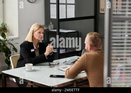 Portrait of caring social worker consulting man behind glass wall in office Stock Photo
