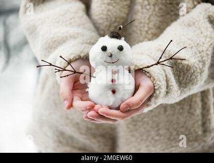 Little cute smiling snowman in the child hands. Having fun in wintertime. Selective focus. Copy space. Stock Photo