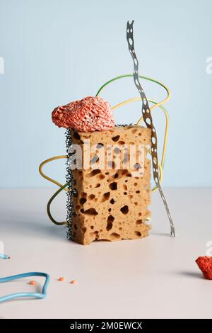 yellow and orange sponge with wire on white, blue background. still life , creative, minimal, contemporary and art concept. balance composition Stock Photo