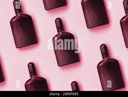 Dark purple perfume bottle with golden ribbon on pastel paper background. Trendy fragrance design Image toned in Viva Magenta, color of the 2023 year Stock Photo