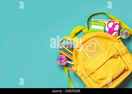 Back to school, education concept Yellow backpack with school supplies - notebook, pens, eraser rainbow, numbers isolated on blue background Top view Stock Photo