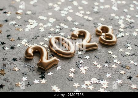 Golden number 2023 on concrete surface sprinkled with confetti Stock Photo