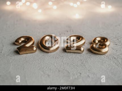 Close-up photo of golden number 2023 on concrete surface with bokeh lights Stock Photo