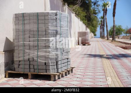 Paving stones on wooden pallet on the street sidewalk. Construction Paving of city streets and adjoining territories. Outdoor tile concrete paving blocks and kerbs Stock Photo