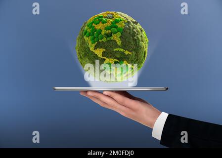 A man is holding a digital tablet. Above this green planet Earth. Symbol of sustainable development and renewable energy Stock Photo