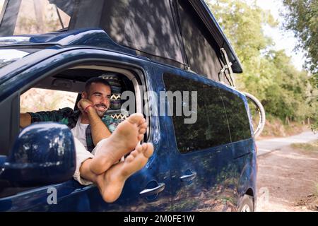 man relaxing sitting on the seat of his camper van Stock Photo