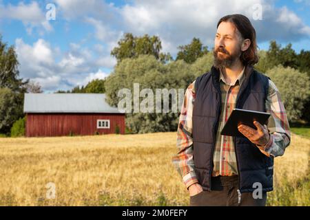 Farmer examines the field of cereals and sends data to the cloud from the tablet. Smart farming and digital agriculture Stock Photo