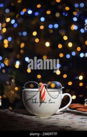 Conceptual Tea Cup Wearing Glasses On Candy Cane Nose with Holidays Bokeh Lights Stock Photo