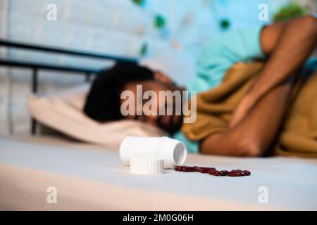 Young man in deep sleep with tablets or medicine pills on bed at night - conept of insomnia medication, unhealthy lifestyle and addiction Stock Photo