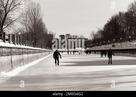 A view of people skating on the Rideau Canal during Winterlude with the Ottawa skyline Stock Photo