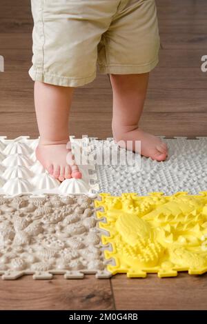 Baby toddler foots close-up on a medical orthopedic mat. Child legs with flat feet on a medical rug. Kid aged one year four months Stock Photo