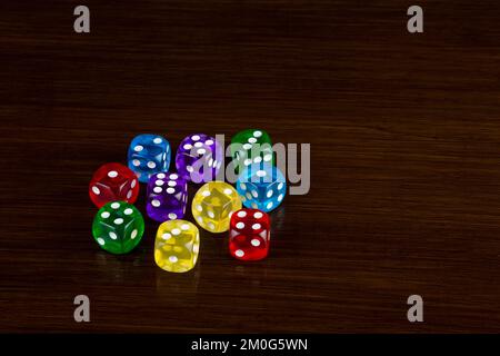 Coloured transparent gaming dice on a polished wooden surface Stock Photo
