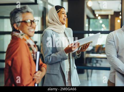 Successful businesspeople laughing happily during a staff meeting in a modern office. Group of cheerful business professionals working as a team in a Stock Photo