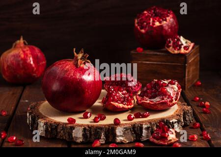 ripe pomegranates on a wooden background. The cut fruits of the pomegranate tree. Stock Photo