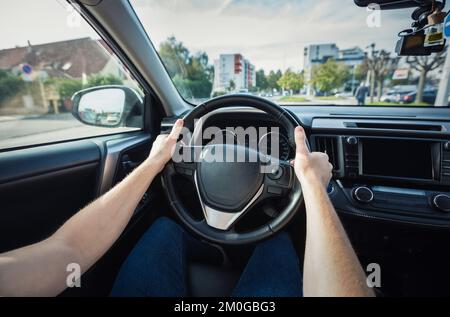 Closeup person hands on the steering wheel, confident driving car on the city streets Stock Photo