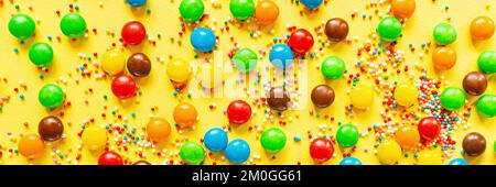 Multicolored candy dragees on yellow background. Top view. Flat lay. Festive, birthday celebration, Easter composition, greeting card. Stock Photo