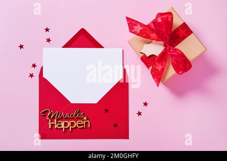 Greeting card mockup, white blank card in envelope and gift box on pink background. Stock Photo
