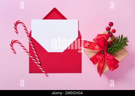 Greeting card mockup, white blank card in envelope and gift box on pink background. Stock Photo