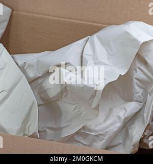 Empty cardboard box with crumpled wrapping paper Stock Photo