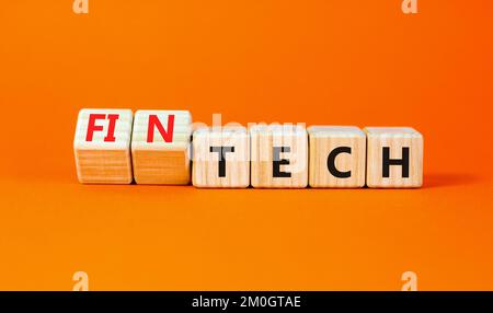 Tech or fintech symbol. Concept word Tech and Fintech on wooden cubes. Beautiful orange table orange background. Business and tech or fintech concept. Stock Photo