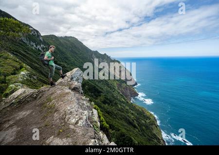 Hiker standing on a ridge, view of steep rocky coast and sea, coastal landscape, Vereda do Larano hiking trail, Madeira, Portugal, Europe Stock Photo