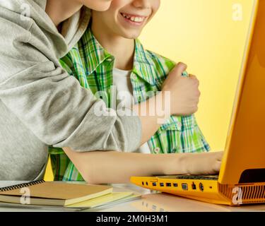 Close up happy Mother with son making video call, looking at laptop screen, talking and smiling on a sunny background. Online charting, communication Stock Photo