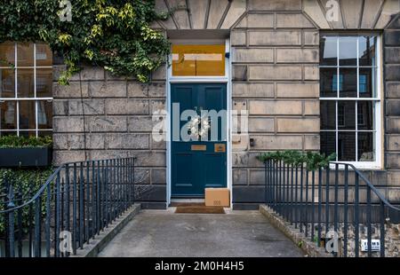 Edinburgh New Town, Scotland, UK, 6th December 2022. Christmas door wreaths and decorations: residents in the Georgian townhouses in the New Town are well-known for their splendid decorations. Pictured: A Christmas wreath on a front door and a Fine Food Specialist parcel left on the doorstep. Credit: Sally Anderson/Alamy Live News Stock Photo