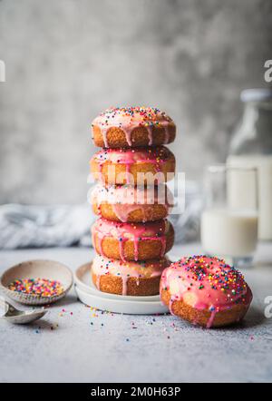 Stack of vanilla cake donuts with pink icing and sprinkles. Stock Photo